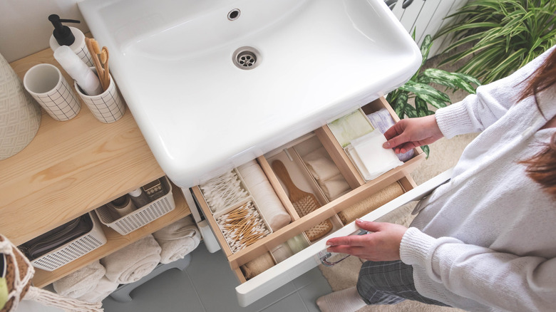 Wooden bathroom sink vanity with open drawer and exposed shelves