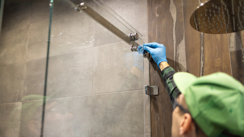 A professional installing a glass shower door.
