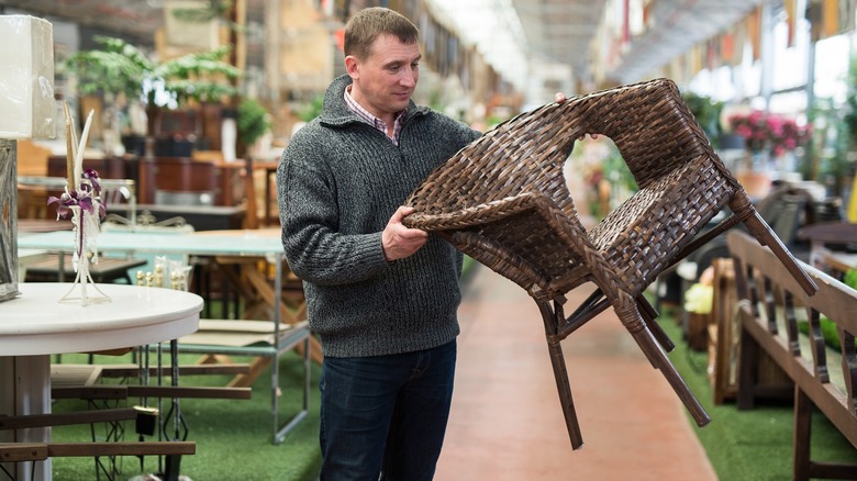 A man looking at a wicker chair