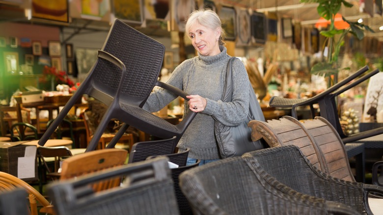 A woman lilfting a wicker chair in a store