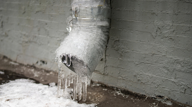 Frozen downspout against building
