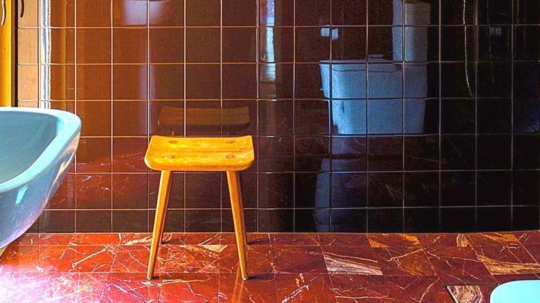 A bathroom featuring red marble floor tiles with matching plain red tiles on the wall