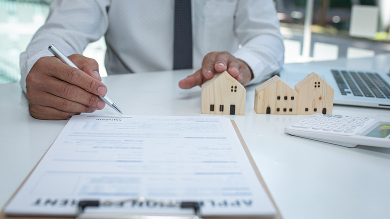 man signing papers on clipboard