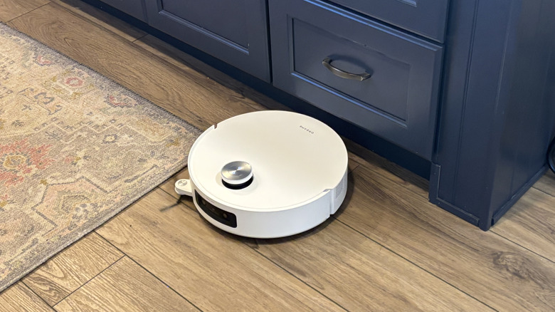 Dreame Aqua10 Ultra Roller vacuuming on hardwood kitchen floor by island cabinets and runner