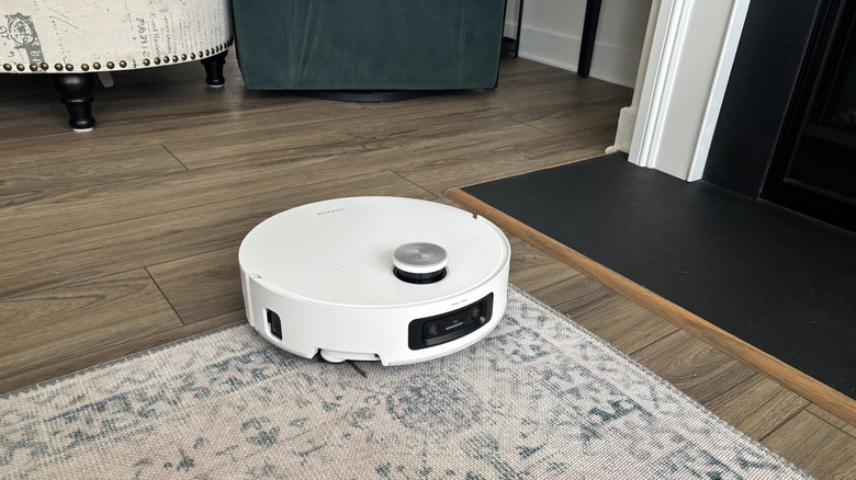 Dreame Aqua10 Ultra Roller cleaning on hardwood floors, half lifted onto area rug, and next to slightly raised fireplace hearth