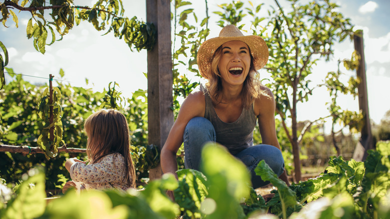 A person wearing a hat and laughing in the garden