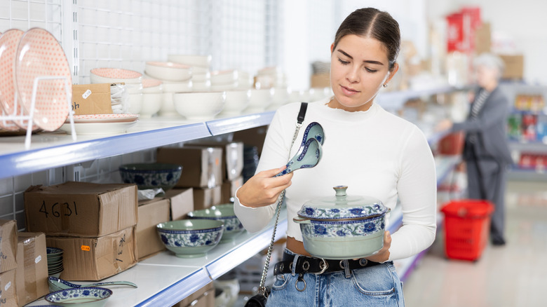 Woman shopping for kitchen dishes and cookware, holding a matching spoon and pot set.