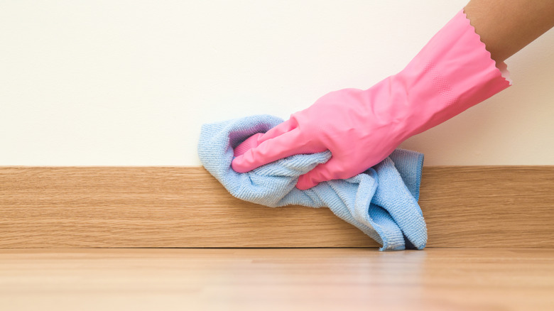 a person dusting a wooden baseboard