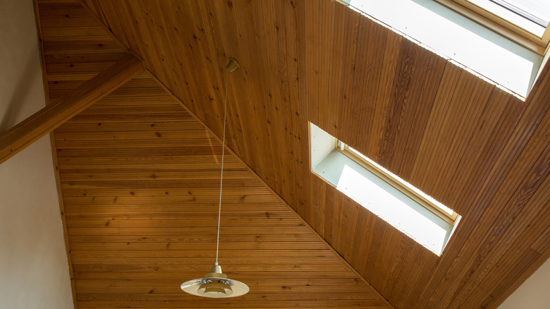 High sloped ceiling with wood paneling and a light fixture