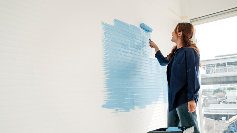 Woman painting her wall a powder blue color