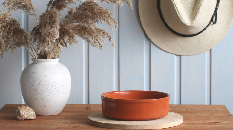 Powder blue-painted shiplap wall behind a warm wood table and terracotta orange bowl