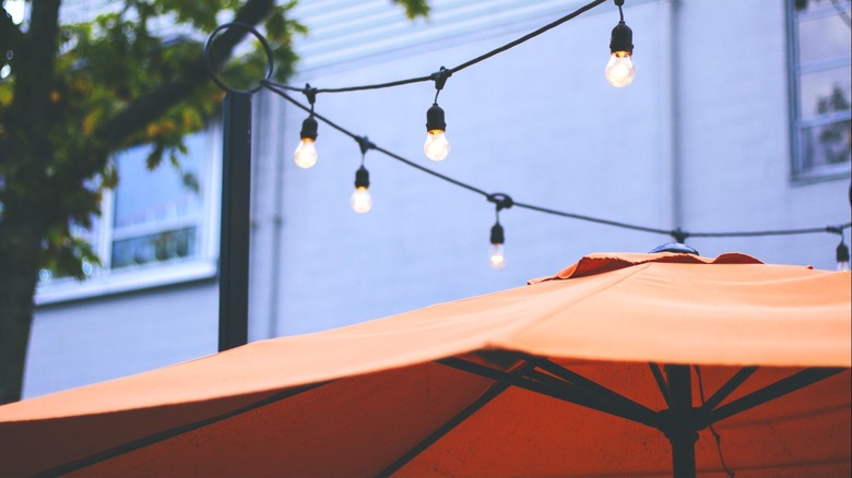 string lights hanging over orange patio umbrella