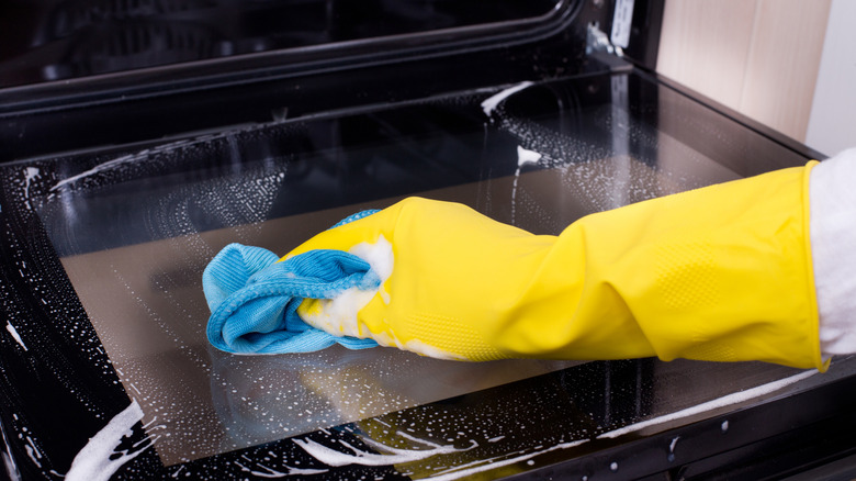 pPerson cleaning oven door with microfiber towel