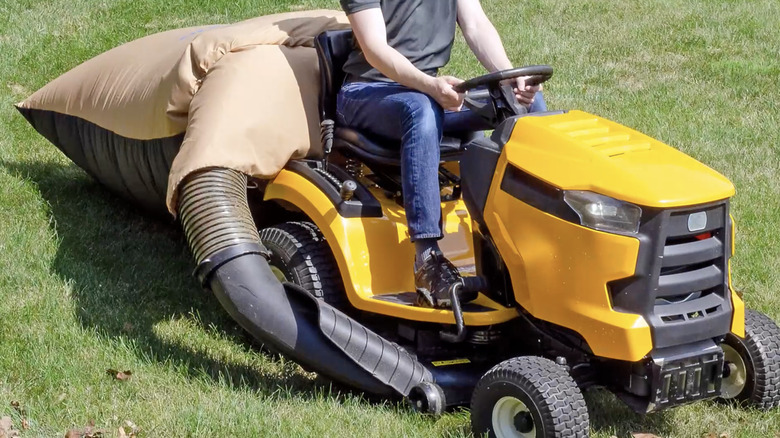 Man using a leaf collection bag on a riding mower