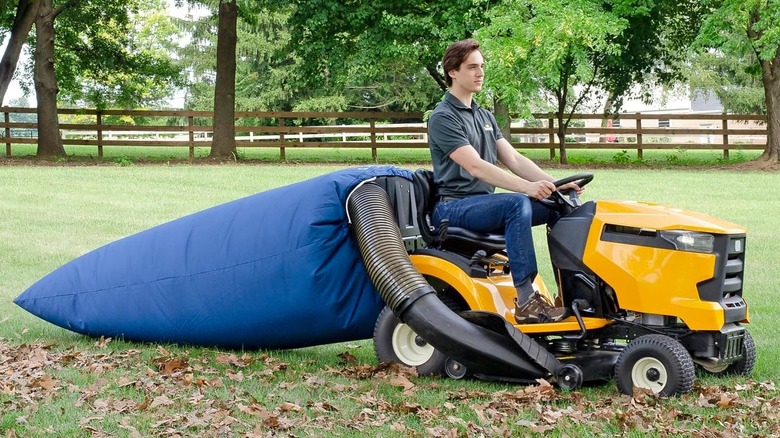 Man riding a mower with a leaf collection bag