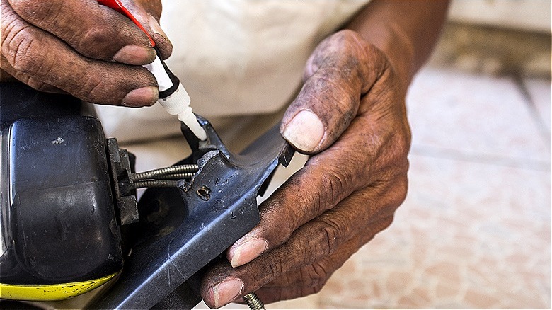 Hands applying glue to metal