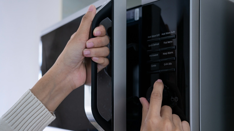 woman opening microwave door 