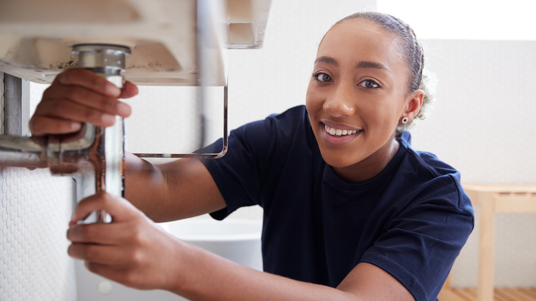 Person fixing leaky sink pipe