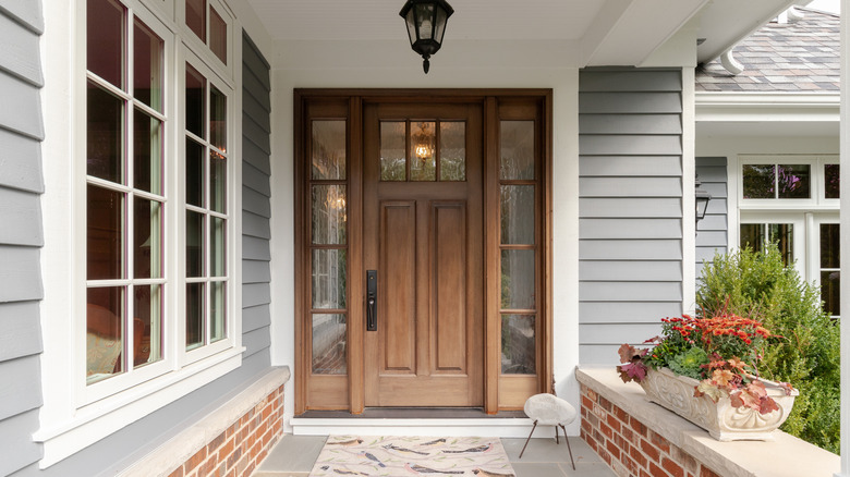 Wooden front door with a hanging ceiling light and gray-and-white walls