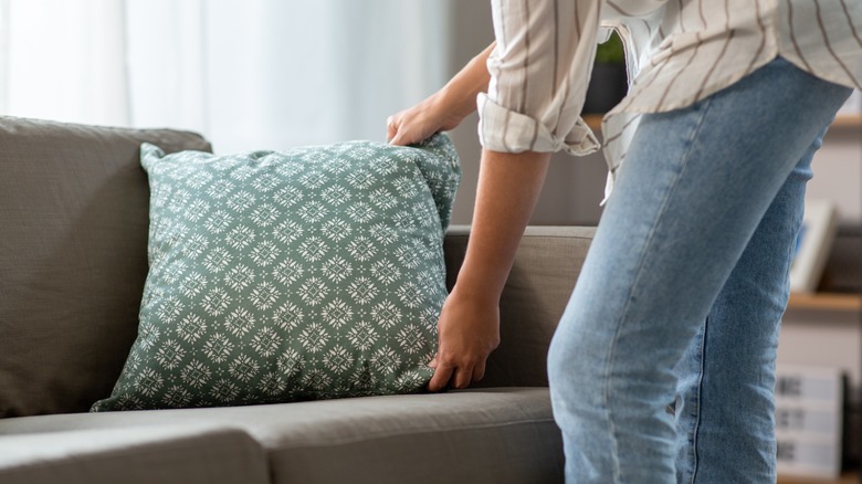 Person fluffing couch pillow