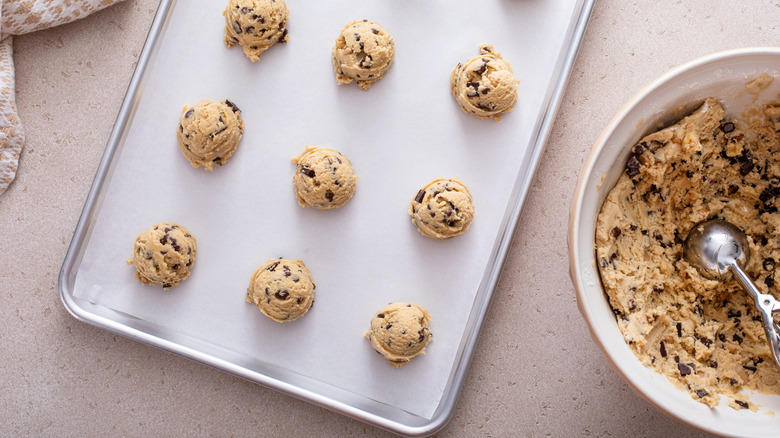 Baking sheet with chocolate chip cookie dough on it.