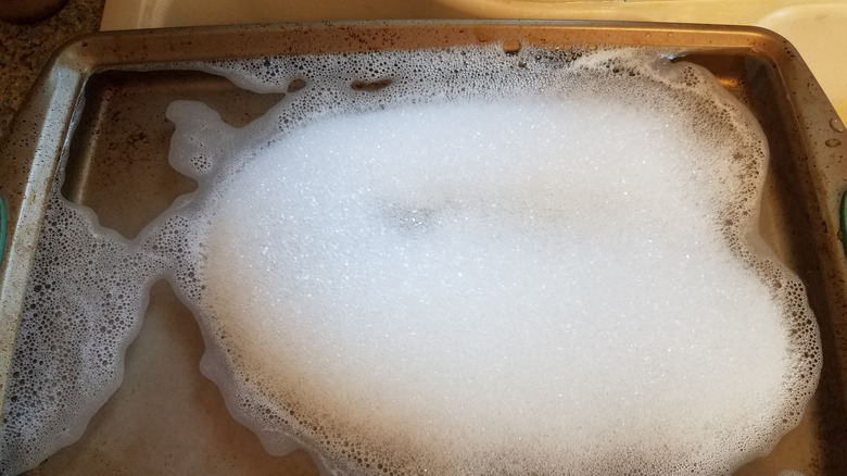 Baking sheet soaking in soapy water.
