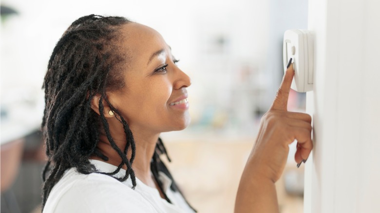 Woman programming a thermostat