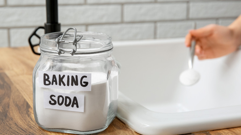 woman using baking soda to unclog her sink