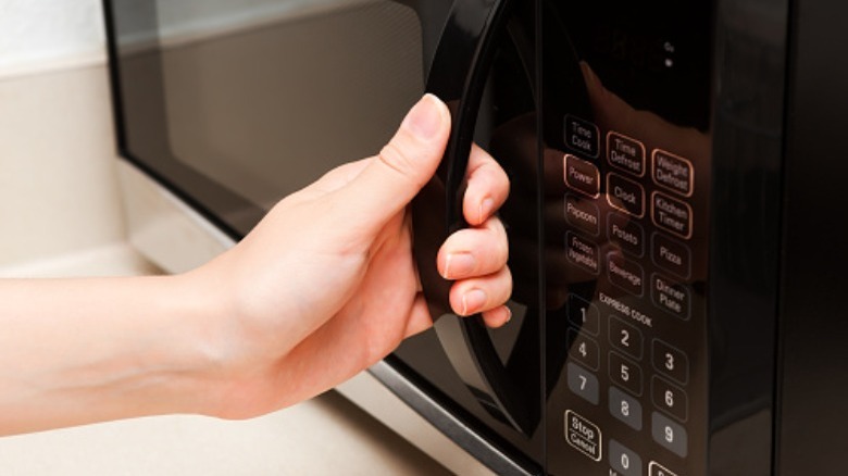 person holding microwave handle
