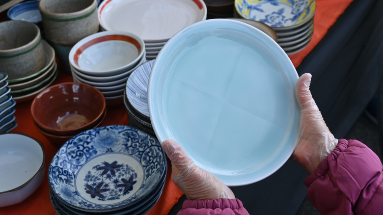 A person picking up a blue plate at a store
