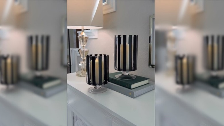 Two glass vases with black vertical stripes holding candles
