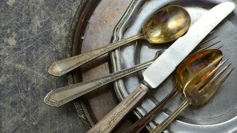 tarnished vintage silverware sitting on metal plate
