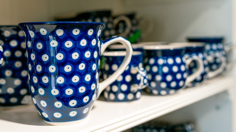 Set of blue ceramic coffee and tea mugs on kitchen shelf
