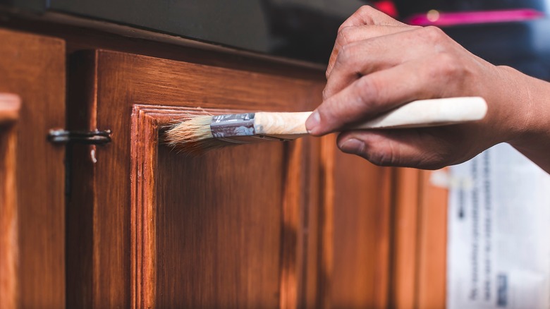 person priming cabinet door