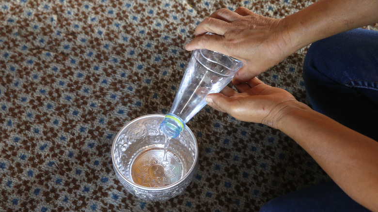 person pouring water into small container