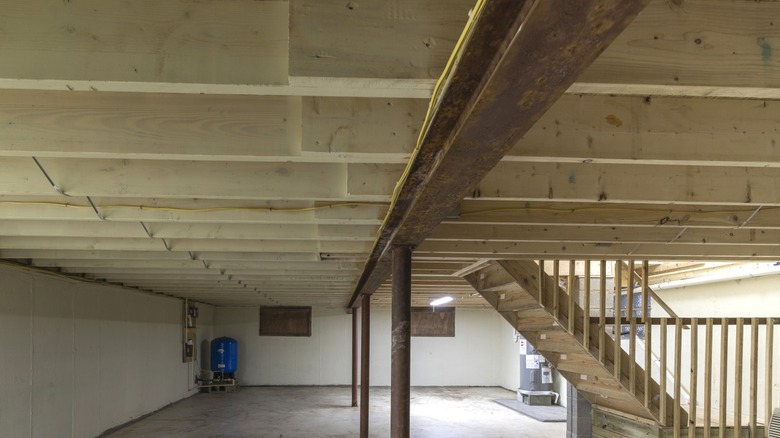 exposed steel support beam under wood floor joists in residential basement