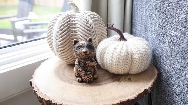 DIY bronzed figurine from Dollar Tree sitting on a small table with woollen pumpkins behind it.