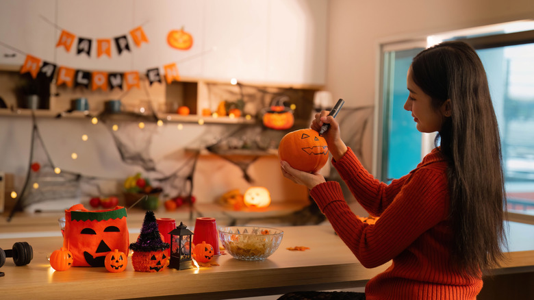 A woman decorates her home for Halloween using crafts