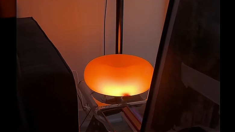 man painting inside of lamp with red nail polish