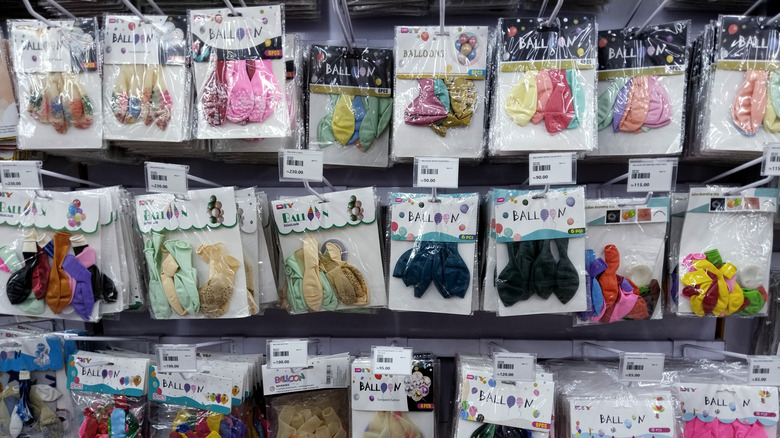 Packaged deflated balloons hanging for sale in a store.