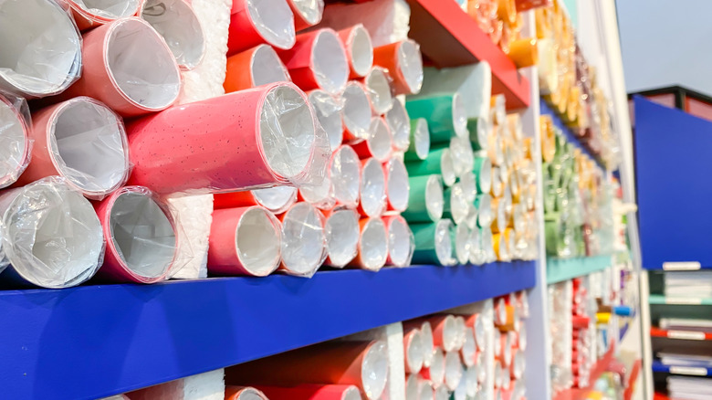 Rolls of colored kraft paper stacked on shelves in a stationery supply store.