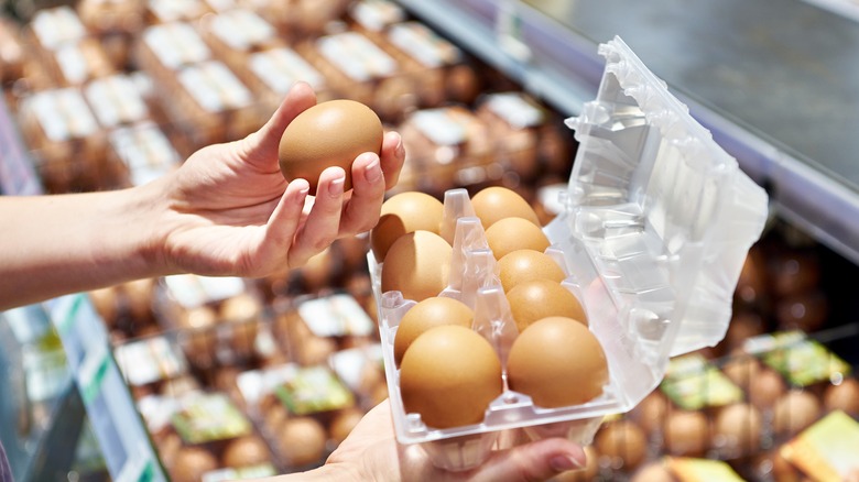 person at grocery store holding an egg carton and an egg in hands