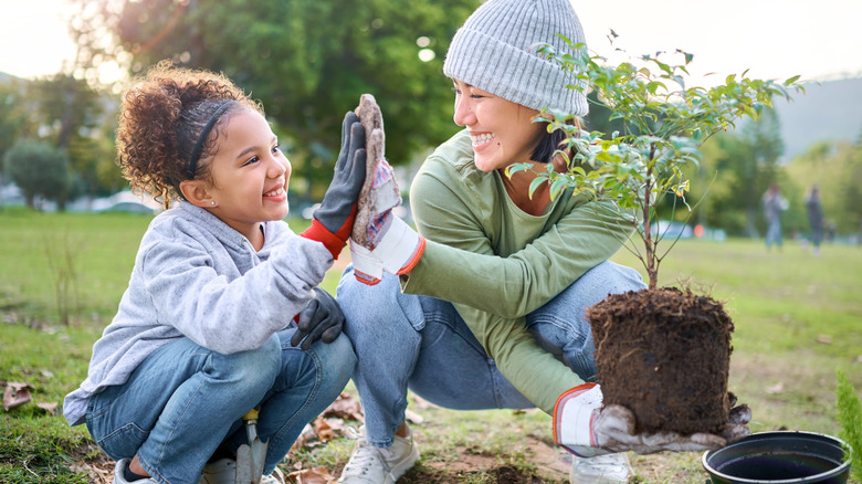 woman high fives child planting tree