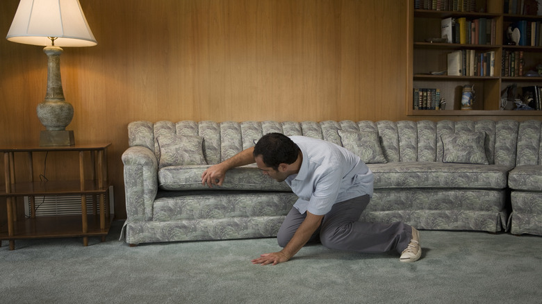 man checks sofa cushions