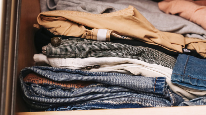 A pile of folded pants on a closet shelf