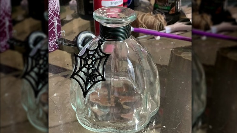 A thrifted glass bottle embellished with Halloween decor