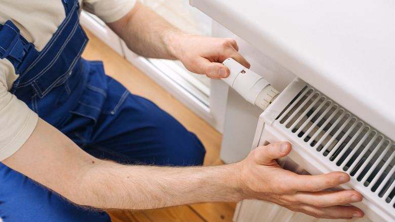 A repairman turns a thermostatic radiator valve