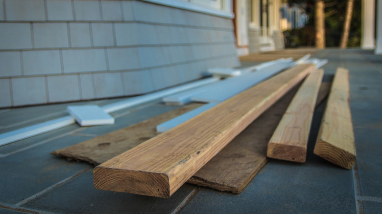 A pile of wood scraps sitting on the front porch of a home.