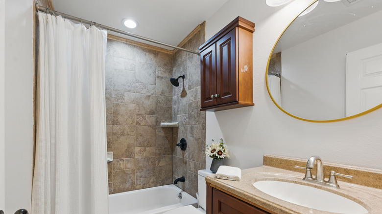 A shower curtain pushed back in a modern bathroom