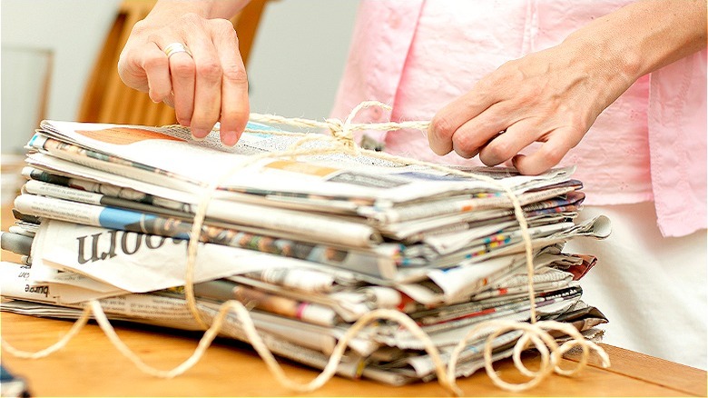 person tying up newspaper stack